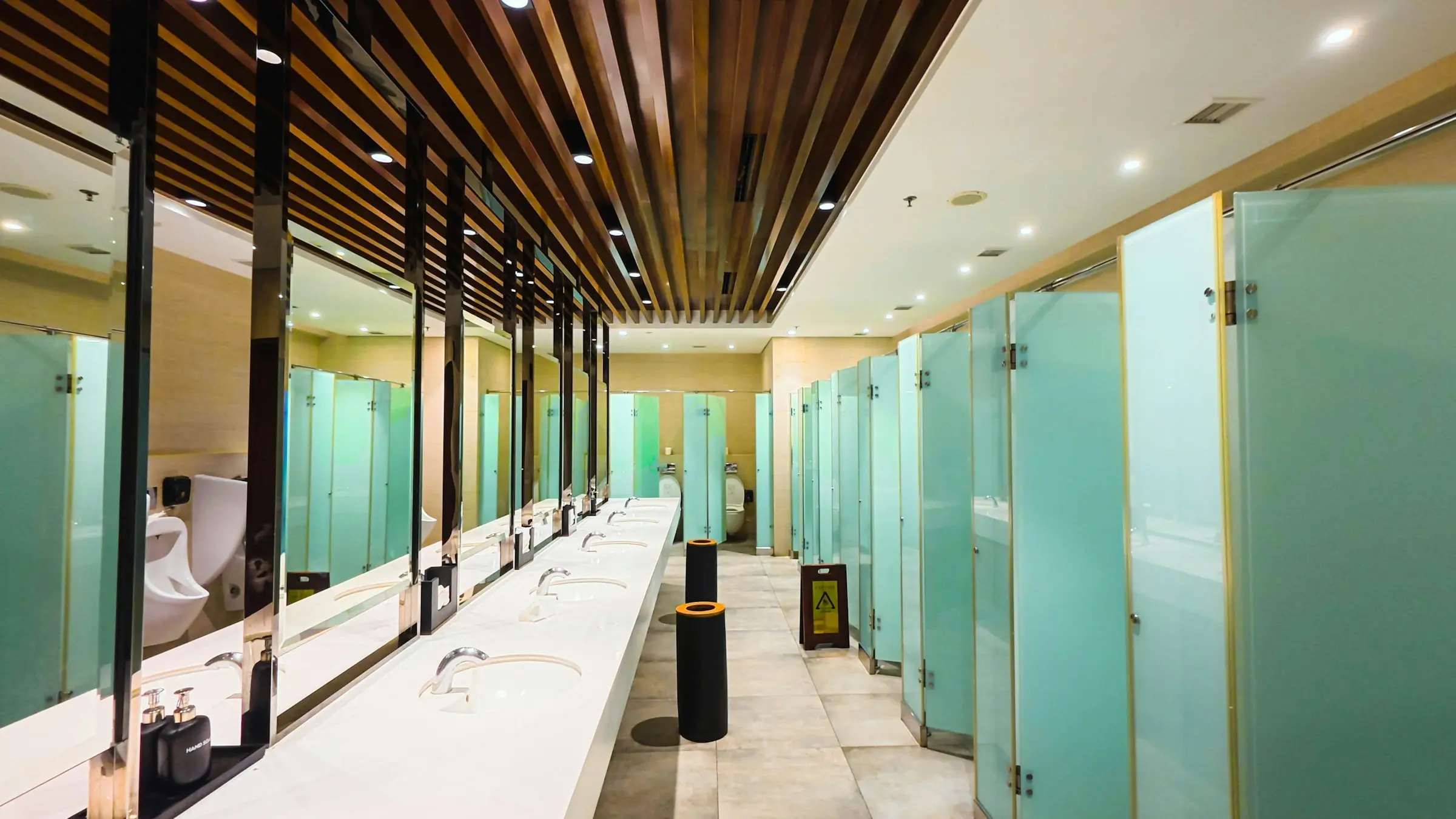 Public restroom with sinks, mirrors, and frosted glass stalls