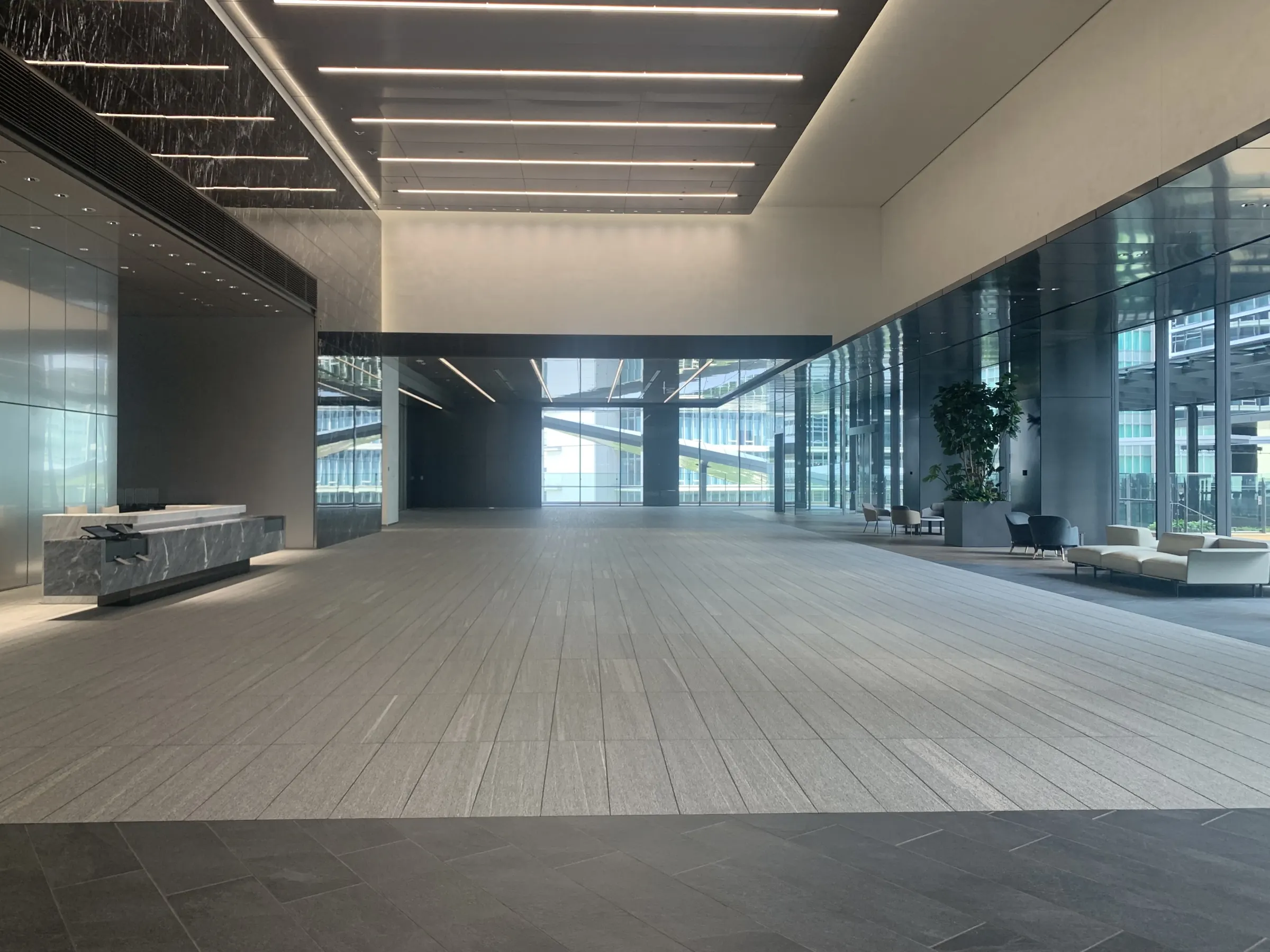 Bright, empty office tower lobby with polished stone floors and a reception desk